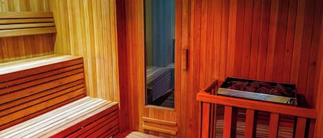 Un sauna avec des bancs en bois et un banc muni d’un plateau en métal.