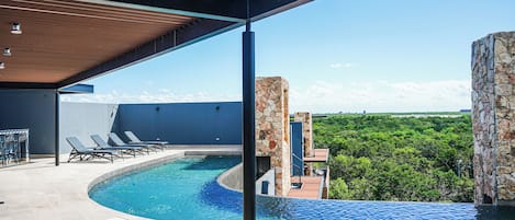 A pool area with lounge chairs and a view of the surrounding landscape.