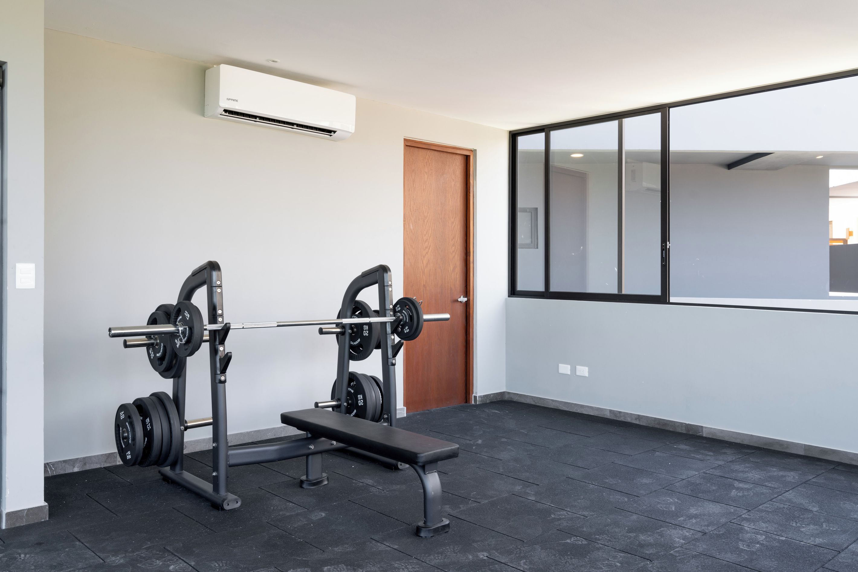 A gym with a weight bench, barbell, and weight plates.