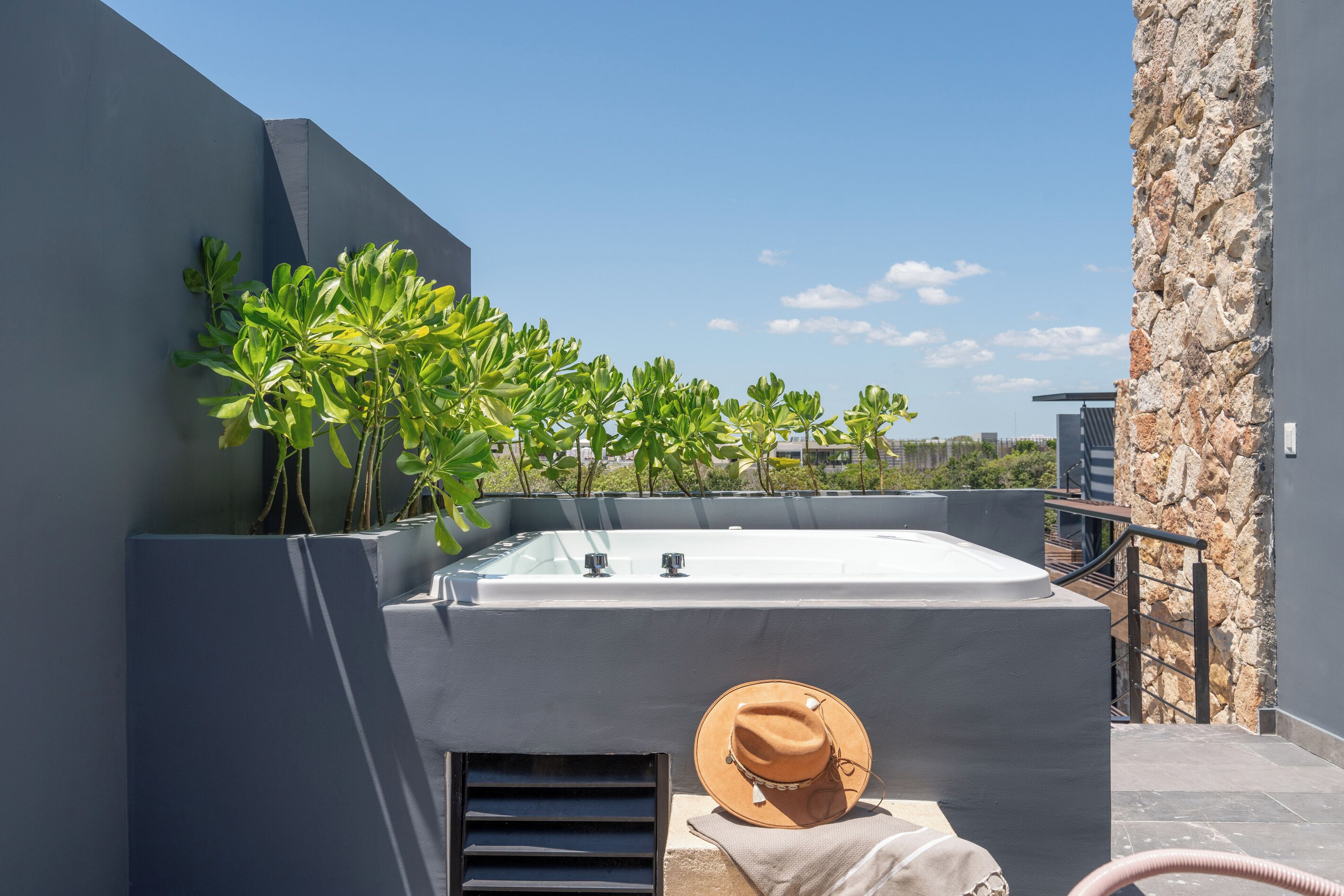 Terraza en la azotea con un jacuzzi, plantas en macetas y un sombrero.