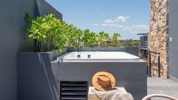 Terraço no telhado com hidromassagem, plantas em vasos e um chapéu.
