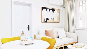 Uma sala de estar moderna com um sofá branco, poltronas amarelas, uma mesa redonda e um quadro na parede.
