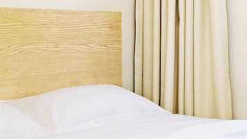 Uma cama com cabeceira de madeira e cortinas bege.