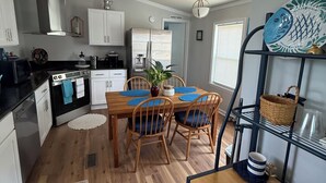 Una cocina moderna con armarios blancos, encimera negra y un área de comedor con sillas de madera y manteles individuales azules.