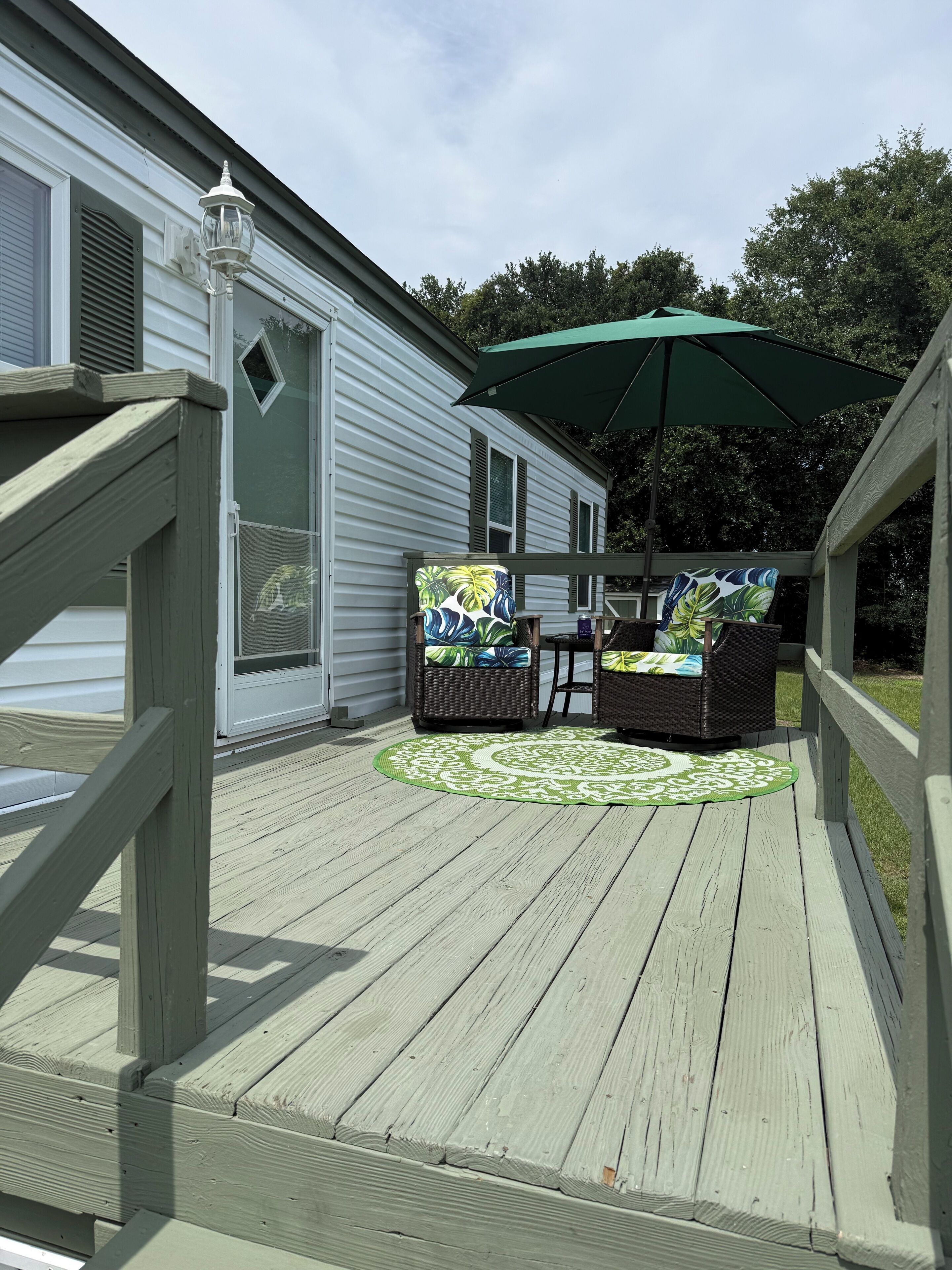 Una terraza con mobiliario exterior y un paraguas verde.