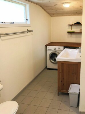 Ein kleiner Waschraum mit Waschmaschine, Spüle und Toilette.