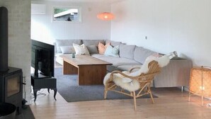 Un soggiorno moderno con un divano, un tavolino in legno, un camino e una poltrona in vimini.