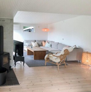 Ein modernes Wohnzimmer mit einer Couch, einem Holztisch, einem Kamin und einem Korbstuhl.