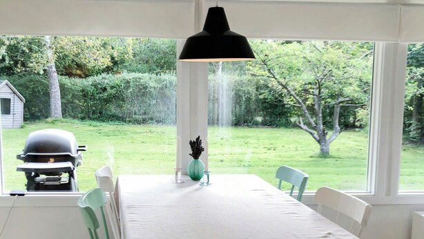 Zona pranzo con tavolo, sedie, lampadario e vista sull'esterno.