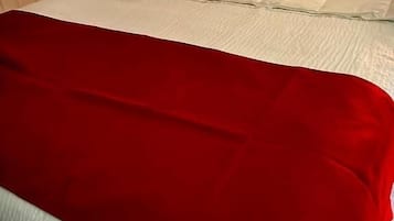 A bed with a white mattress and a red blanket.