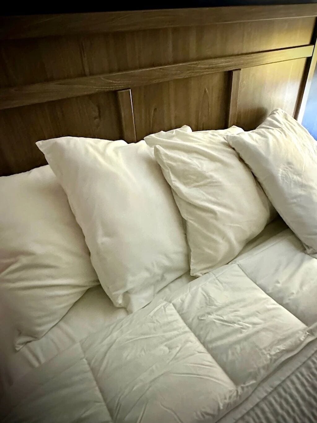 Una cama con ropa blanca y cabecera de madera.
