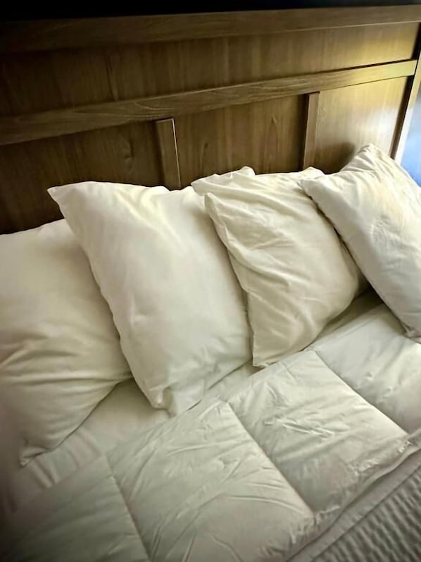 A bed with a wooden headboard and multiple pillows.