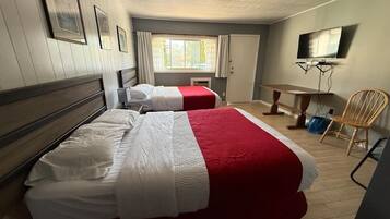 Habitación de hotel con dos camas, televisión, escritorio y una silla.