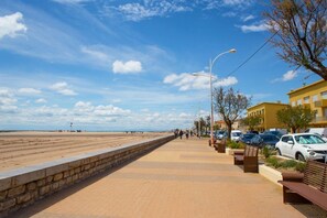 Eine Uferpromenade mit einer Steinmauer, Bänken und geparkten Autos.
