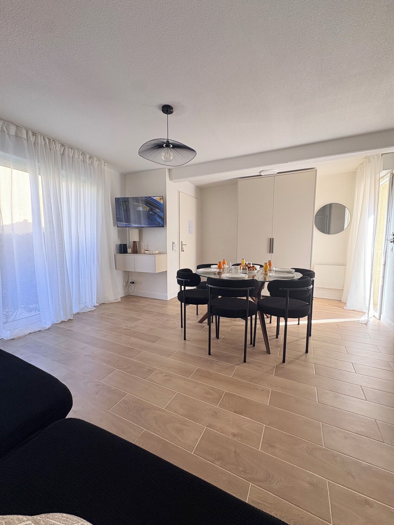 Un salon moderne comprenant un coin repas, un téléviseur à écran plat et un ventilateur de plafond.