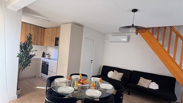 Un espacio moderno para vivir con comedor, cocina y escalera.