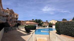 Una piscina rodeada por una valla, con edificios al fondo.