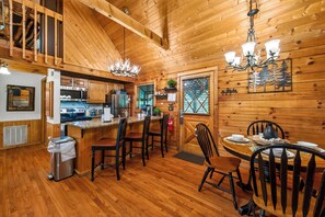 A wooden interior with a kitchen, dining area, and a chandelier. - Smoky Mtn Retreat Hot Tub Fire Table EV Pets OK (Sevierville)