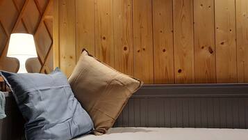 A bed with two pillows, a lamp, and wooden paneling on the wall.