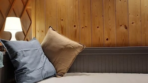 Una cama con dos almohadas, una lámpara y una pared de madera.