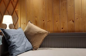 Una cama con dos almohadas, una lámpara y una pared de madera.