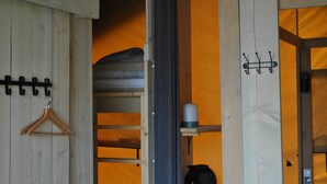 Una habitación con puerta de madera, un perchero, un estante con una taza y un bolso colgado.
