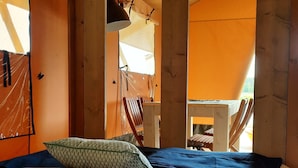 Una habitación con carpa que incluye una cama, almohadas, una silla y una mesa.