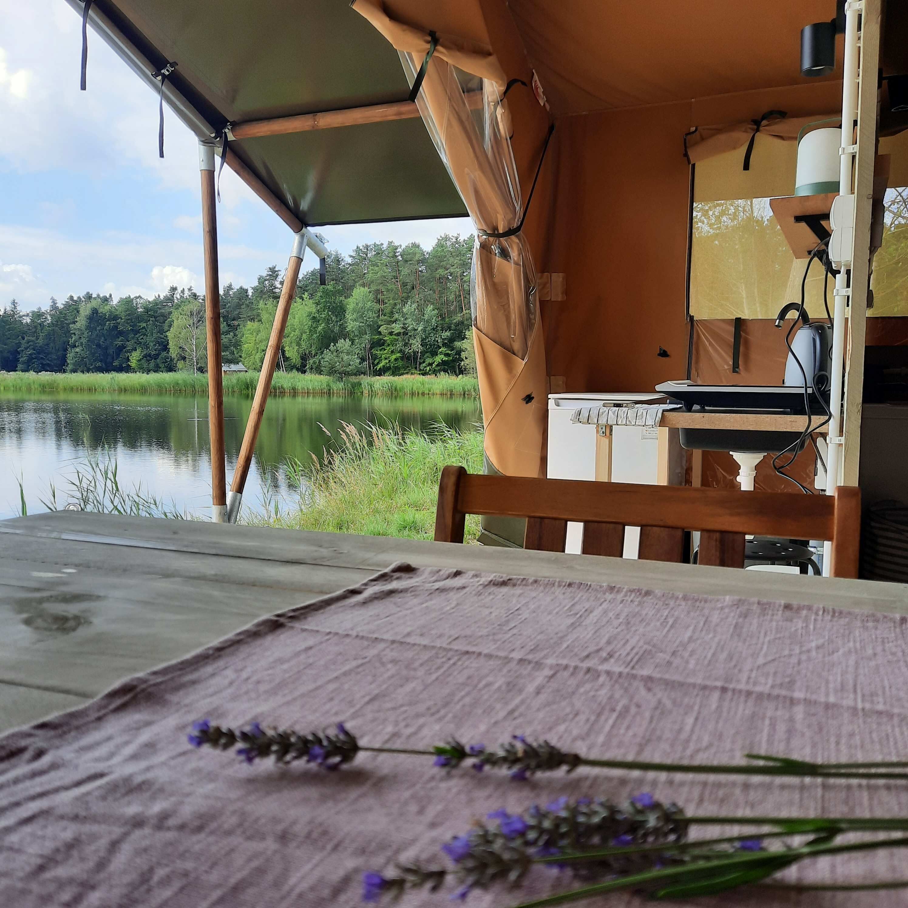 A campsite with a table, a chair, and a tent overlooking a lake.