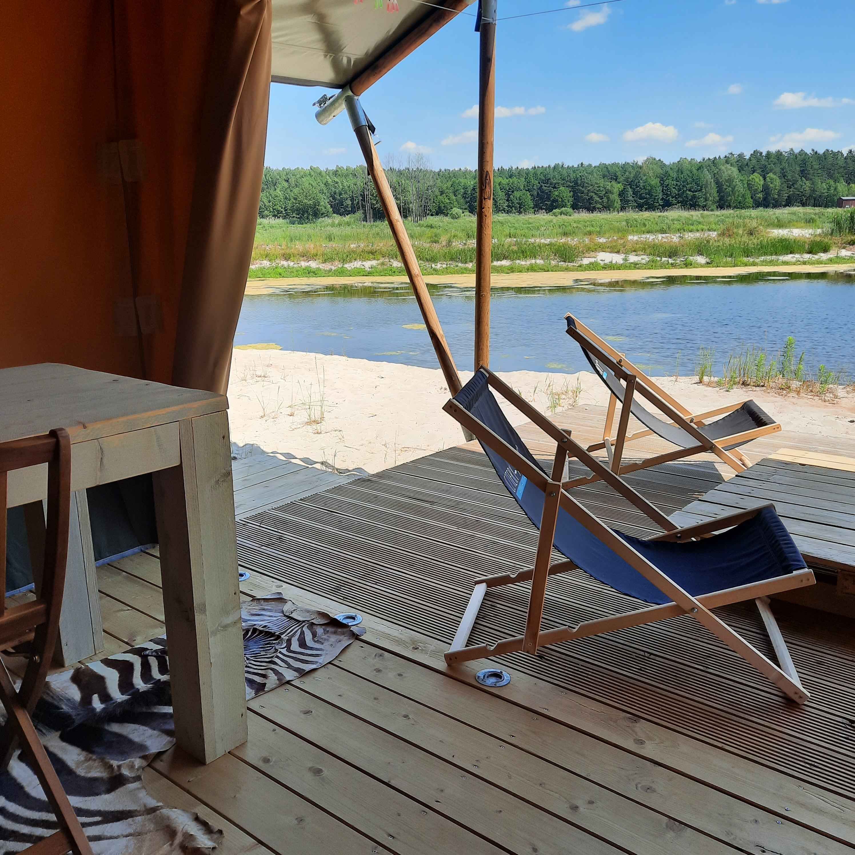 Eine Holzterrasse mit zwei Liegestühlen, einem Tisch und einem zebra-gemusterten Teppich.