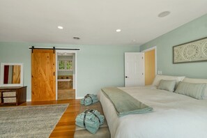 Un dormitorio con una cama, una puerta corredera, una puerta y una obra de arte colgada en la pared.