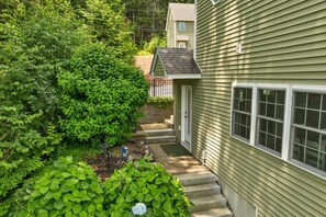 A house with a green exterior, a front porch, and a pathway leading to the entrance. - NEW FOR 2027 Lake Winnipesaukee Waterfront Sleeps 12 (Moultonborough)