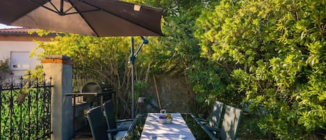 An outdoor patio with a table and chairs, a grill, and a covered area.