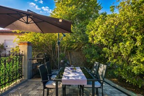 An outdoor patio with a table and chairs, a grill, and a covered area. - Seaview and Terrace Apartment La Vita (Kostrena)