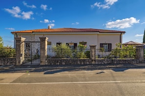 A two-story house with a tiled roof, a stone wall, and a metal gate. - Seaview and Terrace Apartment La Vita (Kostrena)