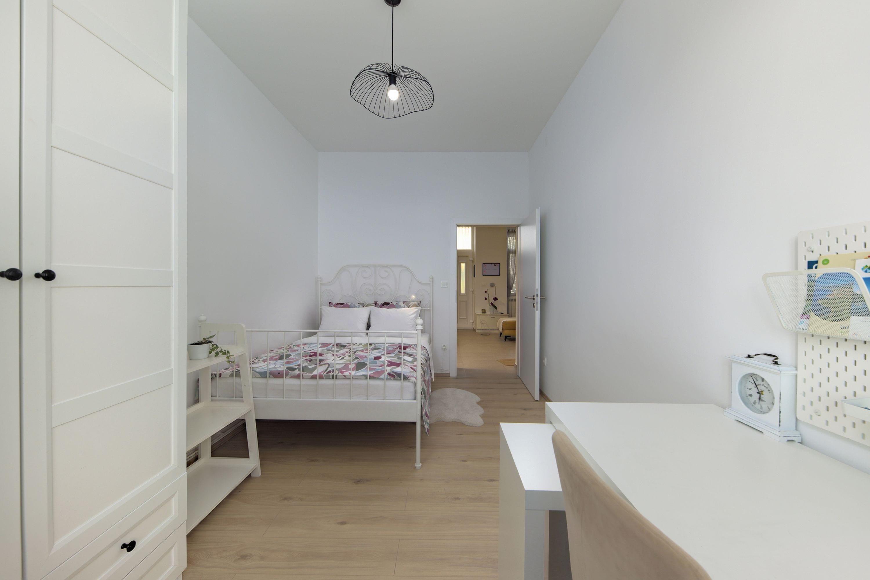 Une chambre à coucher avec un lit, une table de chevet et un luminaire suspendu.