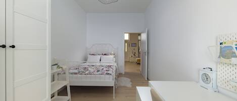 Un dormitorio con cama, mesita de noche y lámpara colgante.