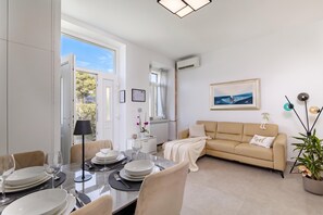 Ein modernes Wohnzimmer mit Essbereich, einer Couch, einem Gemälde und einer Topfpflanze.