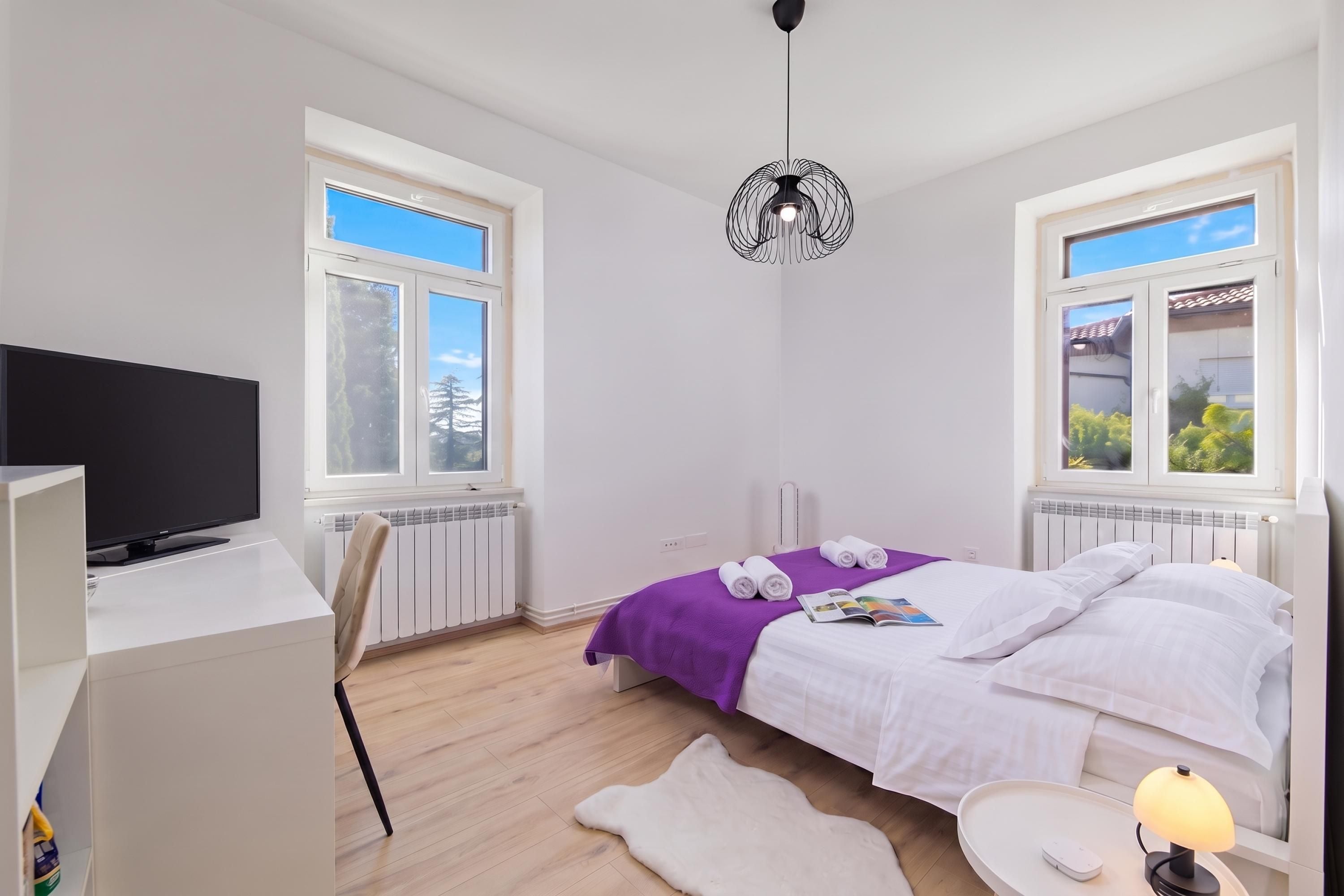 Une chambre à coucher moderne, comprenant un lit, un bureau, une chaise, une lampe et un radiateur.