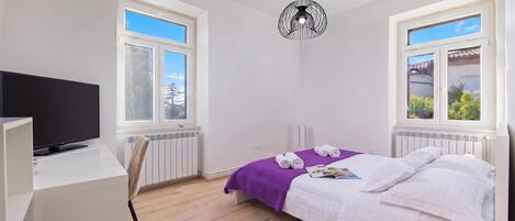 A modern bedroom with a bed, a desk, a chair, a lamp, and a radiator.