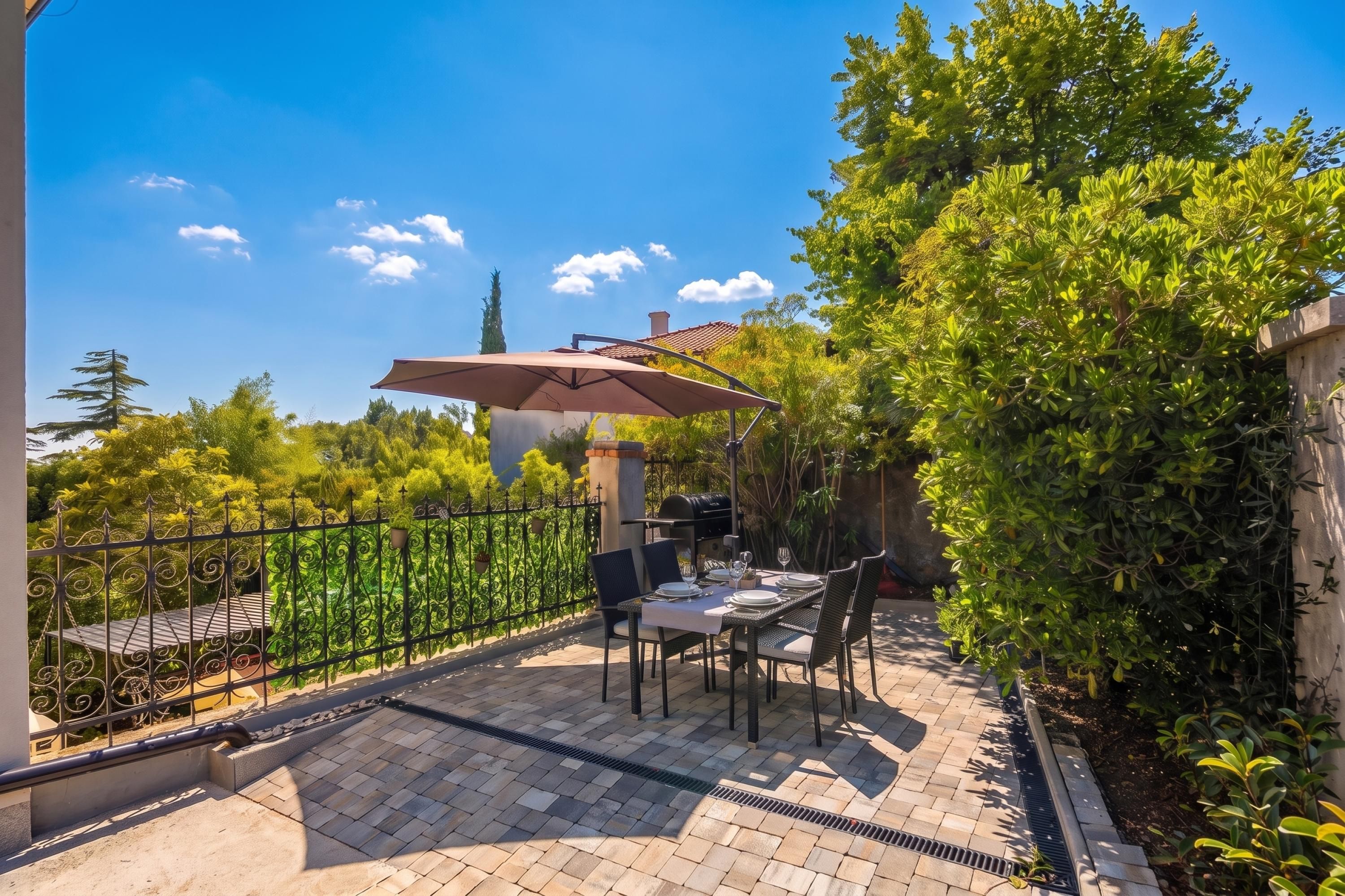 A patio with a table and chairs, a grill, and a pergola.