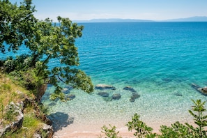 A coastal landscape with clear turquoise waters, rocky shoreline, and lush greenery. - Seaview and Terrace Apartment La Vita (Kostrena)