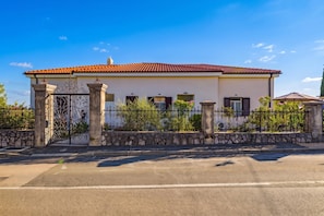 A two-story house with a tiled roof, a stone wall, and a metal gate. - Seaview and Terrace Apartment La Vita (Kostrena)
