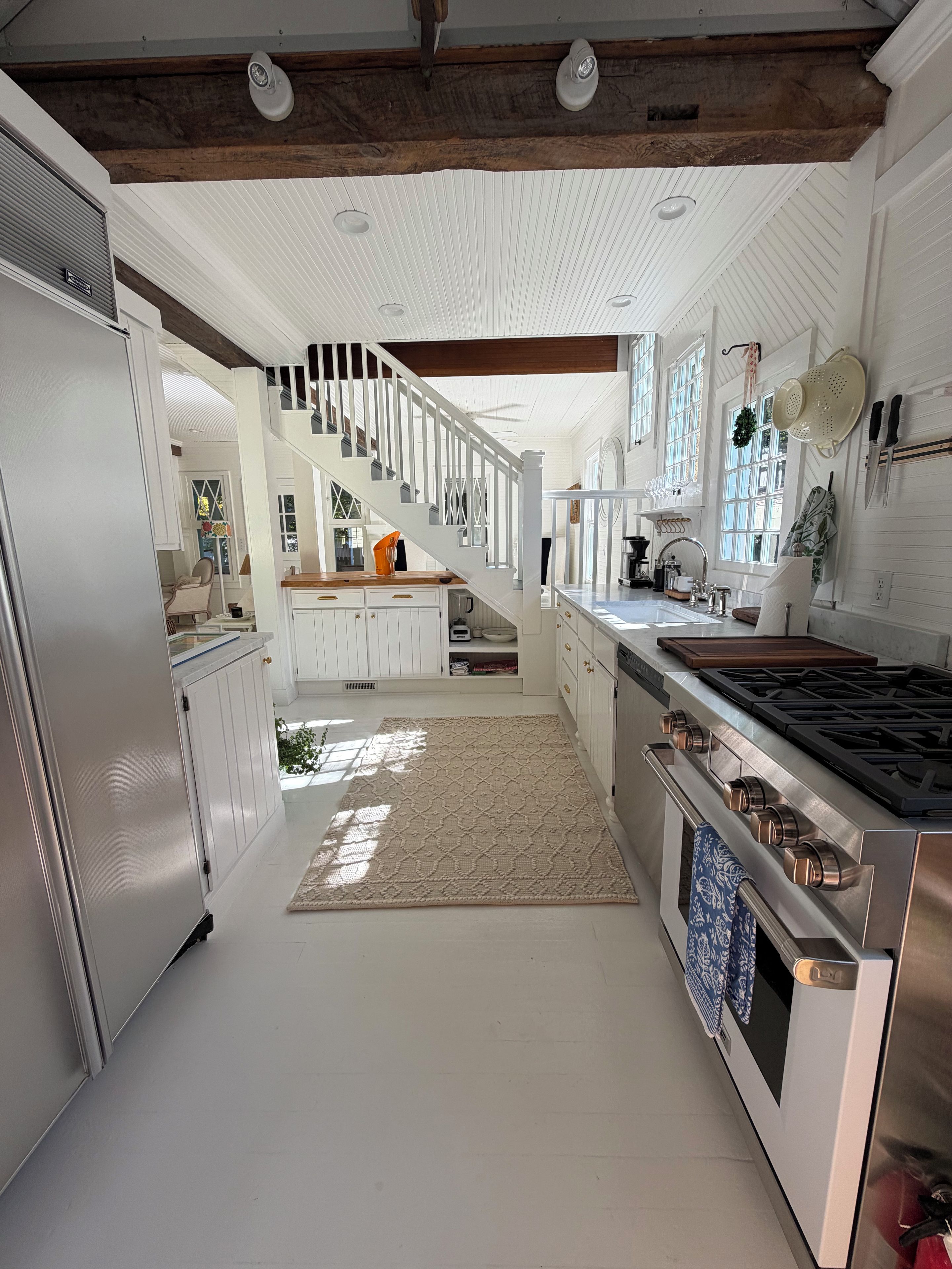 A spacious kitchen with a central island, stainless steel appliances, and a wooden staircase.