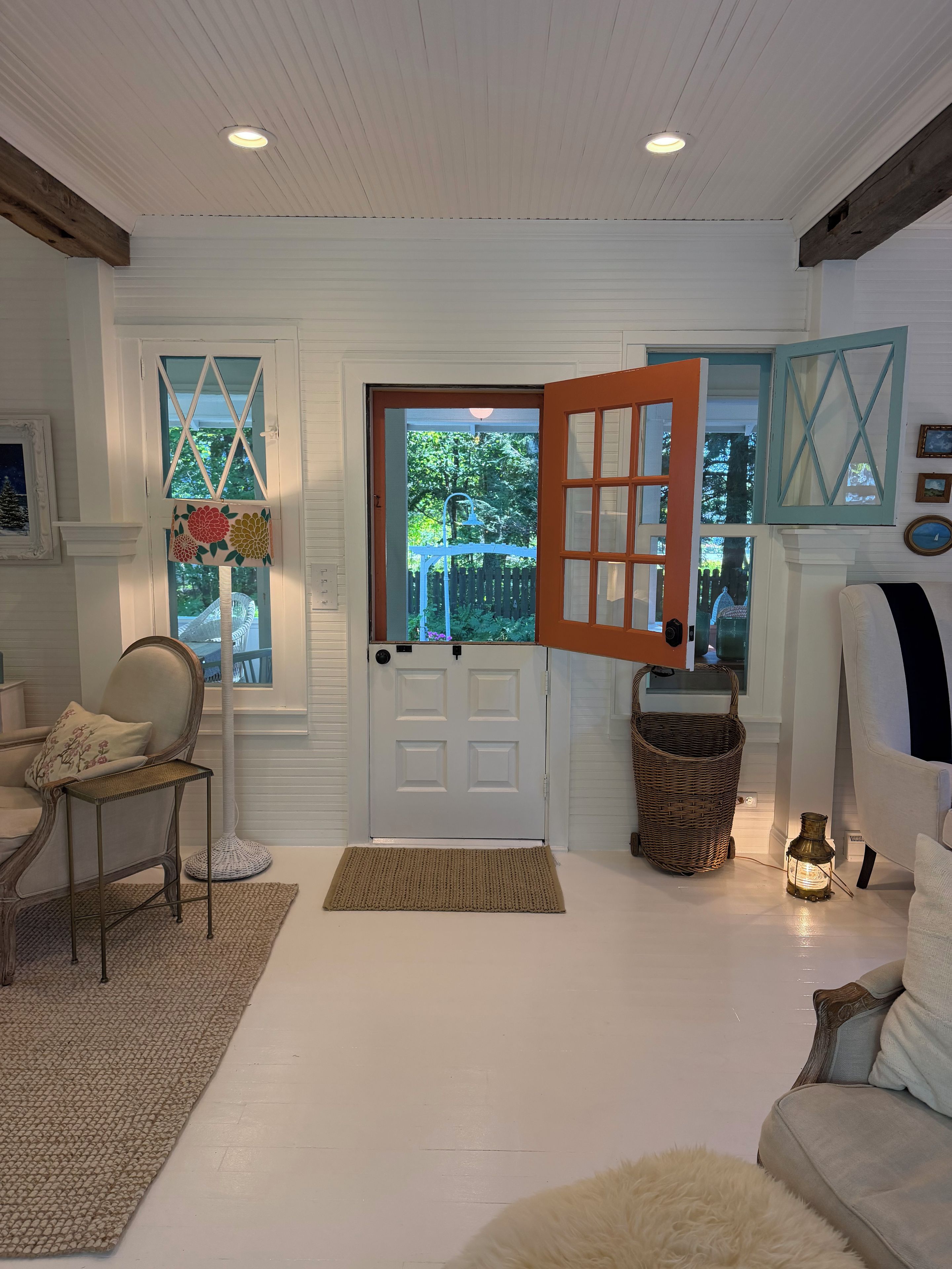 A room with a white door, a wicker basket, a lamp, and a chair.