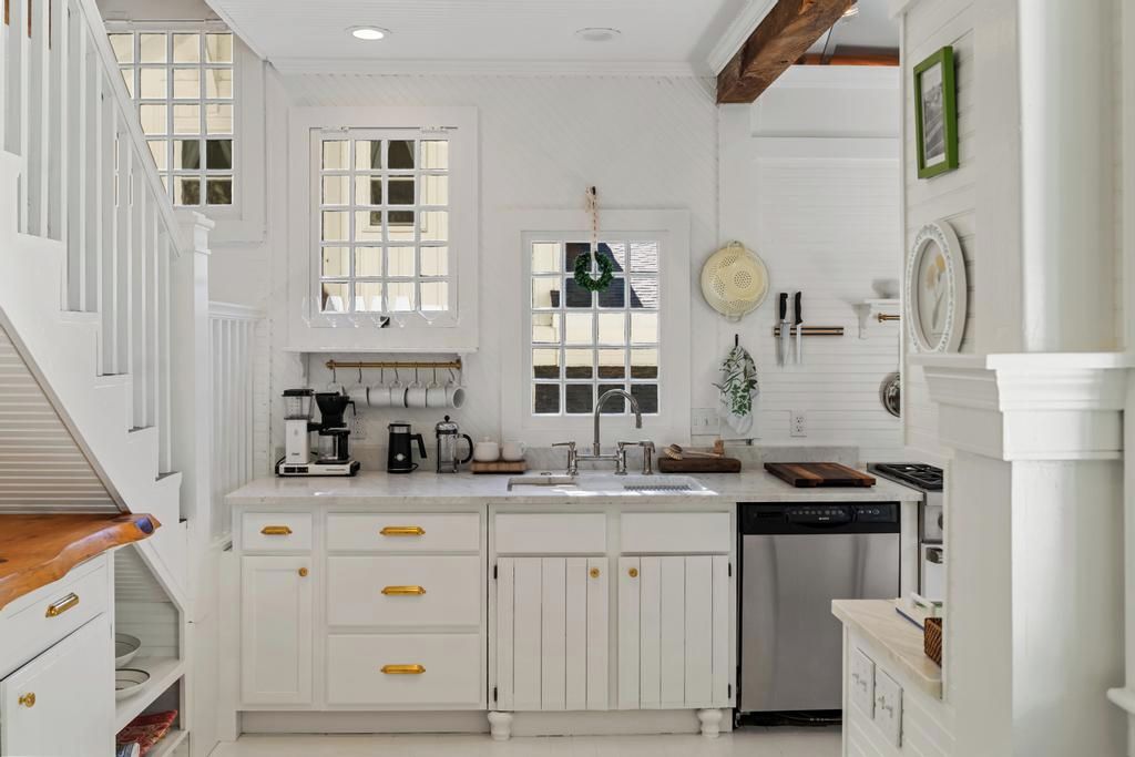 A kitchen with white cabinetry, a dishwasher, and a coffee maker.