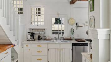 A kitchen with white cabinetry, a dishwasher, and a coffee maker.