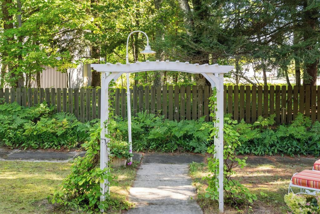 A garden with a white arbor and a pathway leading to a seating area.