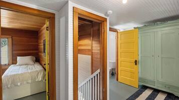 A bedroom with a bed, a wooden wardrobe, and a yellow door.