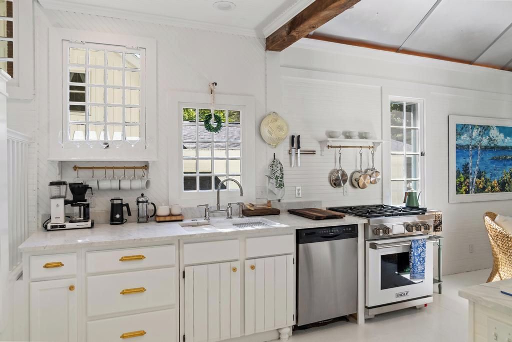 A kitchen with white cabinetry, a stove, a dishwasher, and a coffee maker.