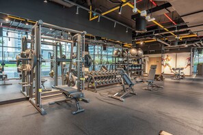 Un gimnasio moderno con equipo de levantamiento de pesas, una prensa de banca y mancuernas.